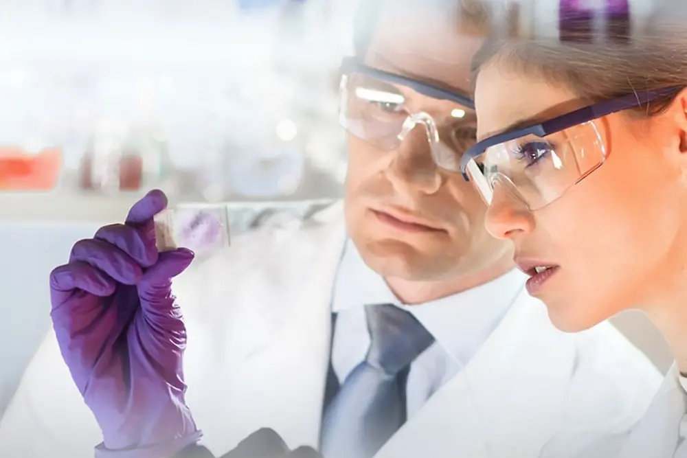 Visages d'une femme et d'un homme examinant un échantillon dans un laboratoire