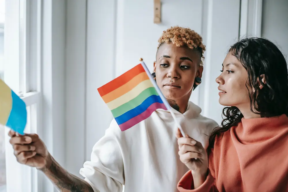 Deux femmes se parlent en tenant un drapeau LGBTQ+.