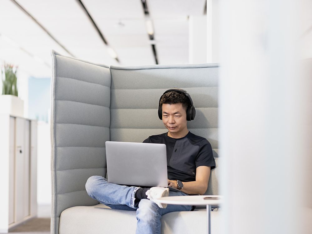 Un employé de Henkel avec des écouteurs travaille concentré sur son ordinateur portable. 