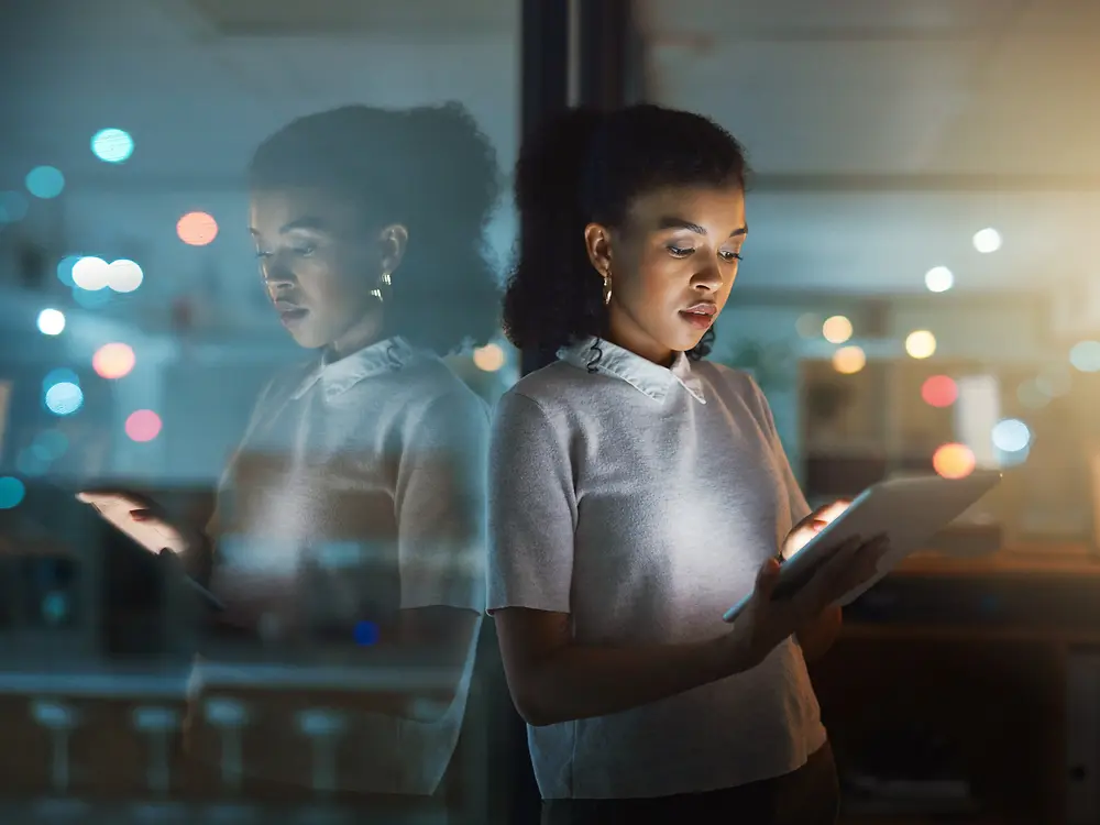 Une femme tape sur une tablette, l'air concentré et attentif.