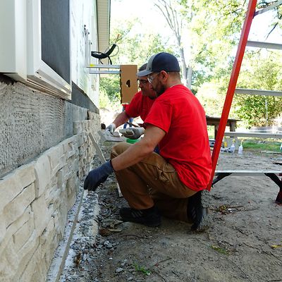 Two men repairing brick wall