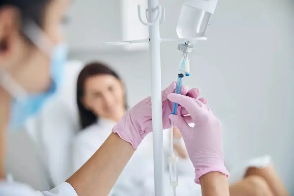 Un professionnel de santé tient une poche de perfusion intraveineuse dans un établissement de soins.